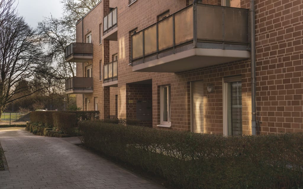 Ein Mehrfamilienhaus aus Backstein mit Balkonen.