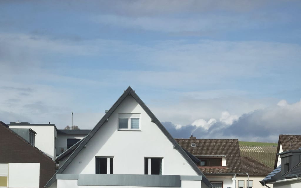 Ein weißes Wohnhaus mit Satteldach vor blauem Himmel