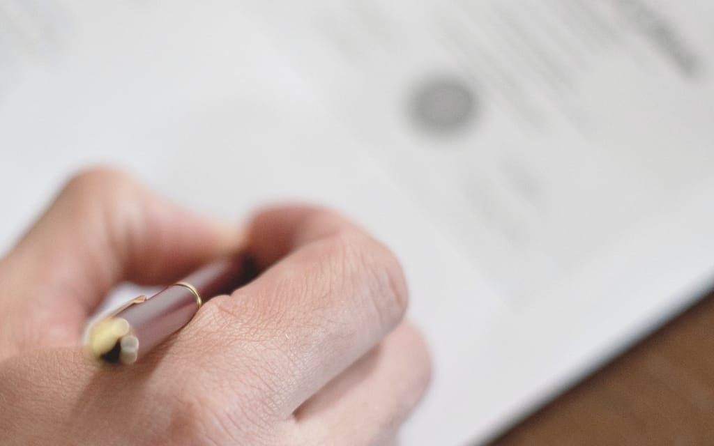 Eine Hand mit Füller auf einer Urkunde